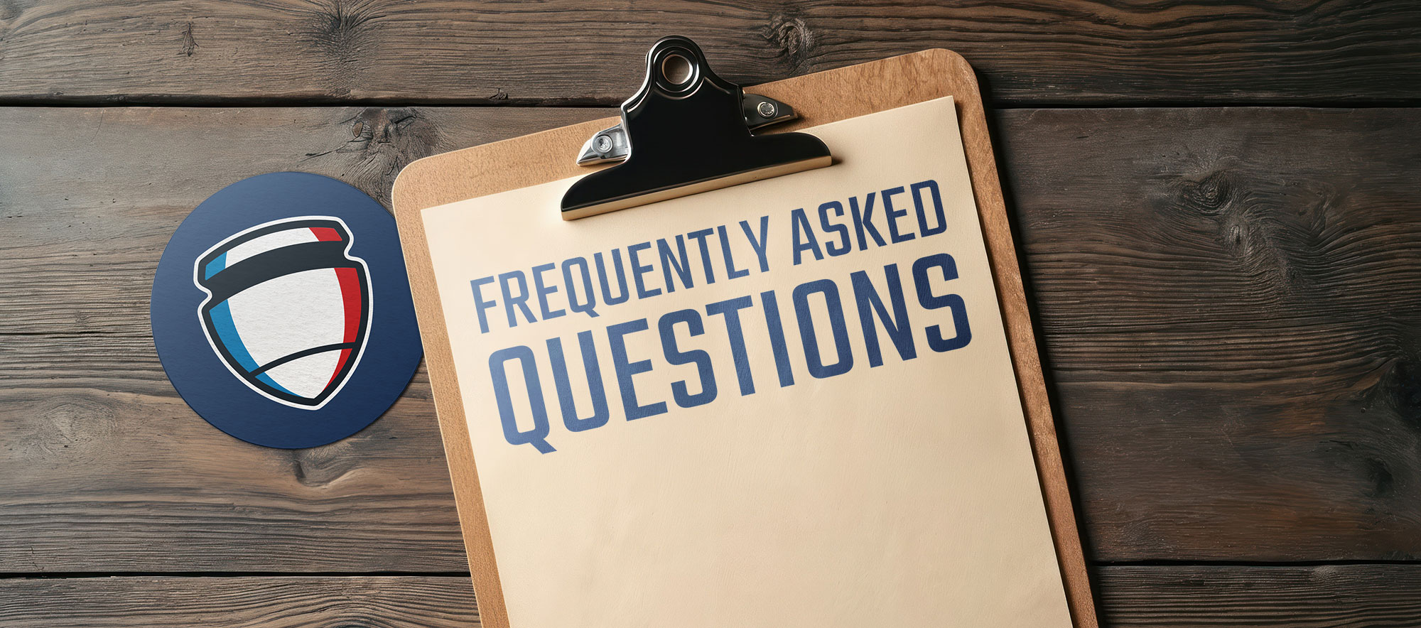 Frequently Asked Questions text on a piece of paper on a clipboard with a coaster that has the Central Illinois Training Academy logo symbol on it, both of which are resting on a rustic wood surface background.